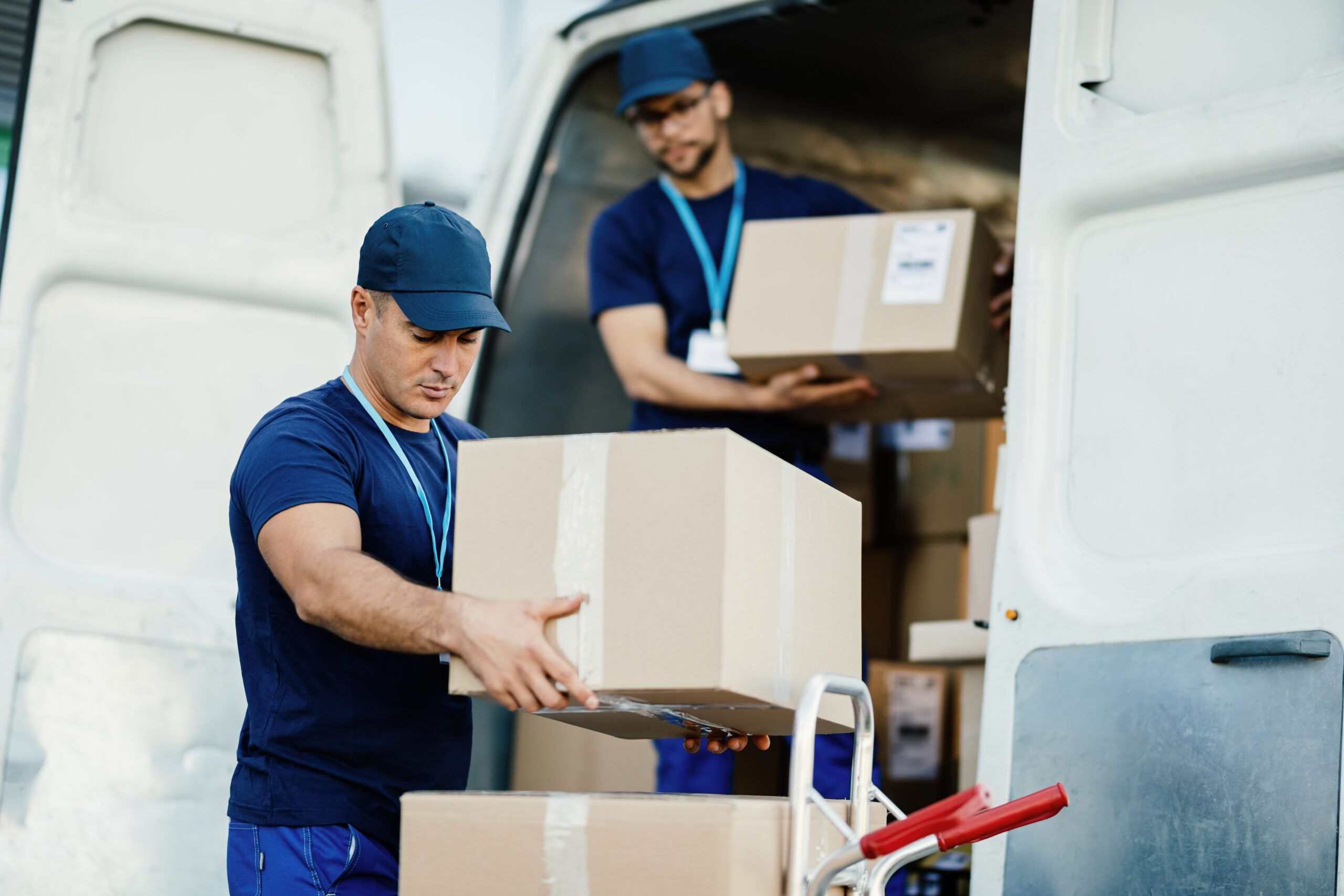 young delivery man and his coworker unloading boxes from a van.
